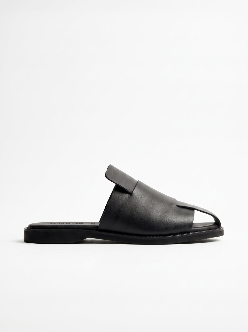 A single black leather slide sandal with a wide strap and a small decorative tab on the instep, shown in profile against a plain white background.