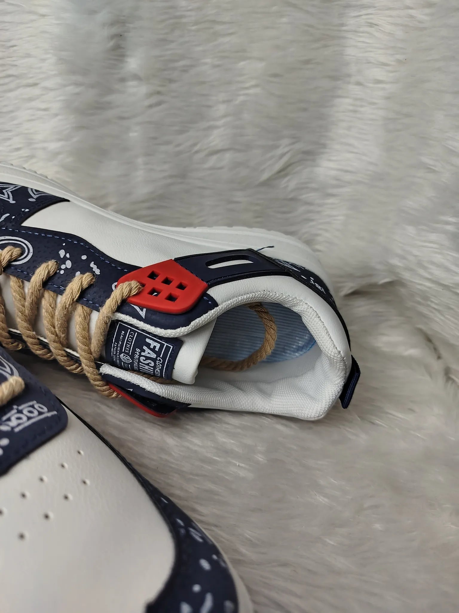 Close-up of a white sneaker with blue and red accents on a textured surface - BlackBole High Quality Shoe
