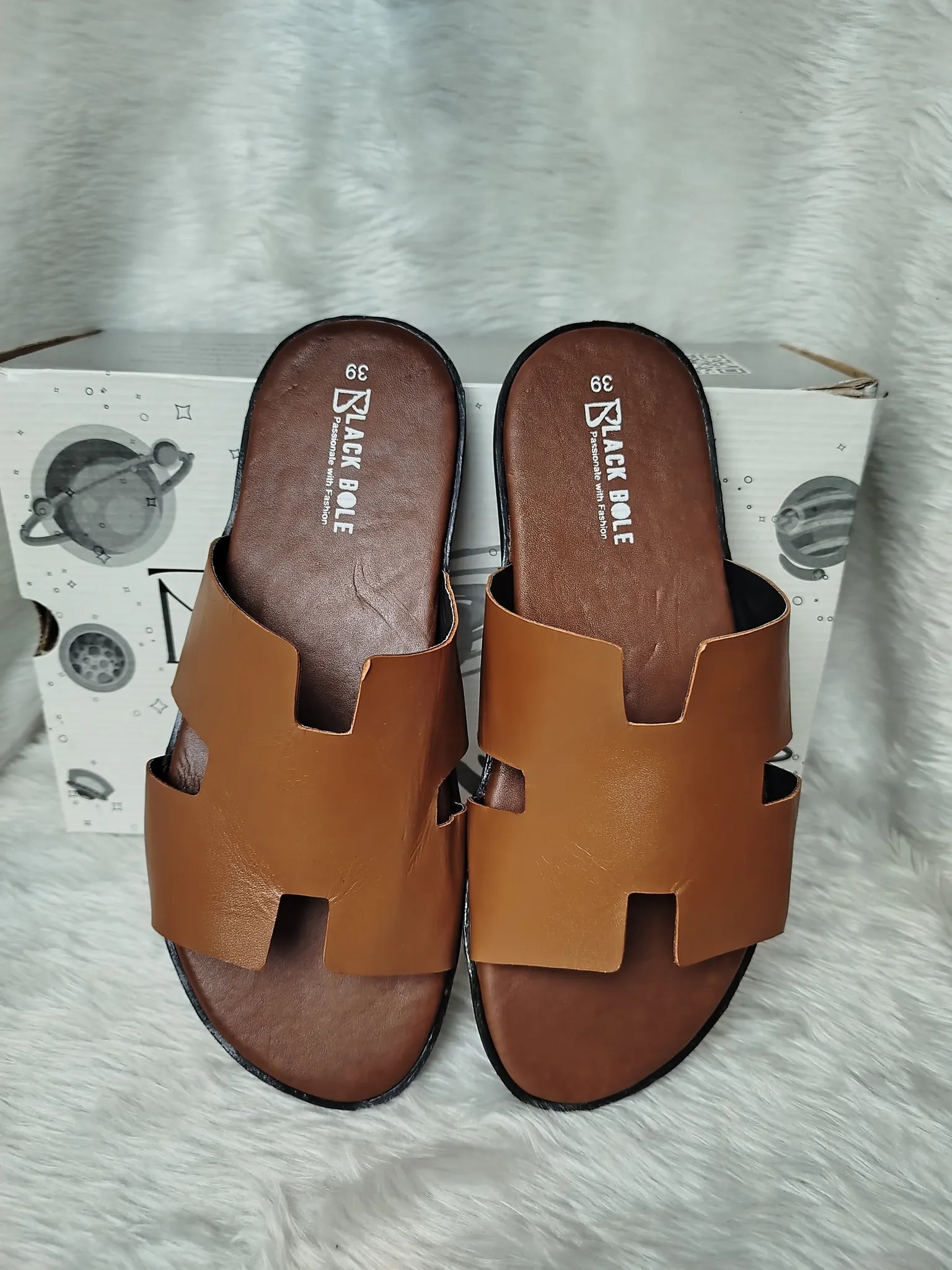 Pair of brown sandals on a white box with visible brand name - BlackBole High Quality Sandal