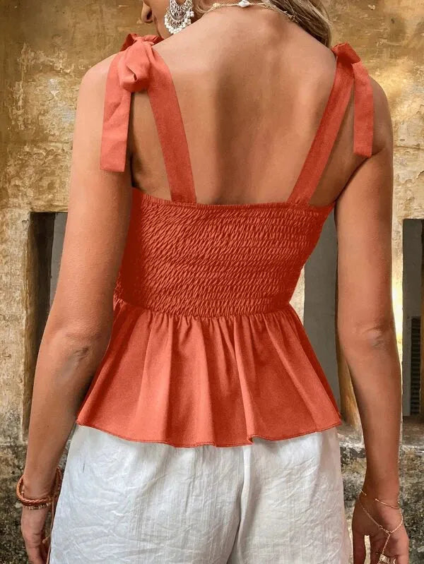 Woman wearing a coral peplum top with bow straps against a stone wall background - BlackBole High Quality Western Dress