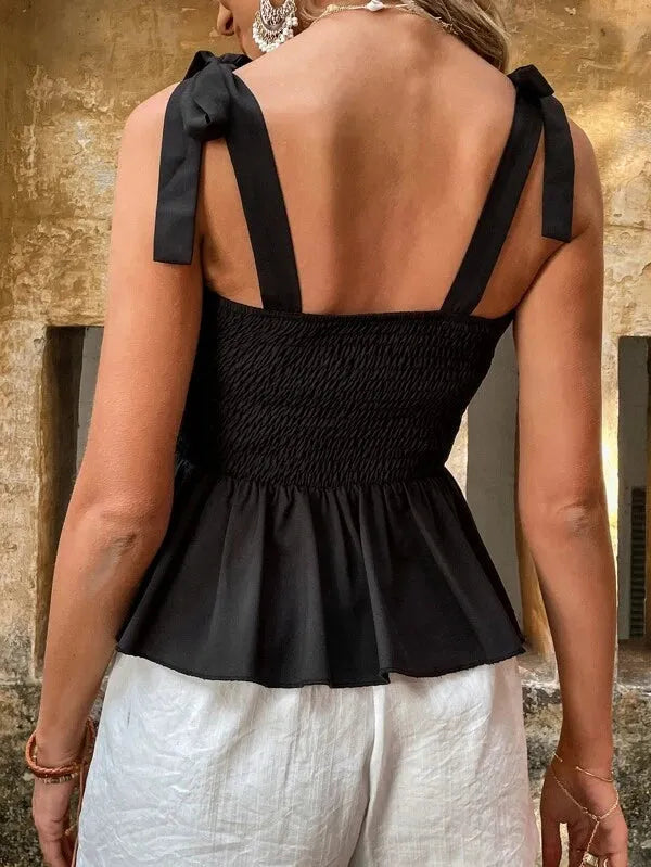 Black peplum top with bow straps worn by a person against a textured wall - BlackBole High Quality Western Dress