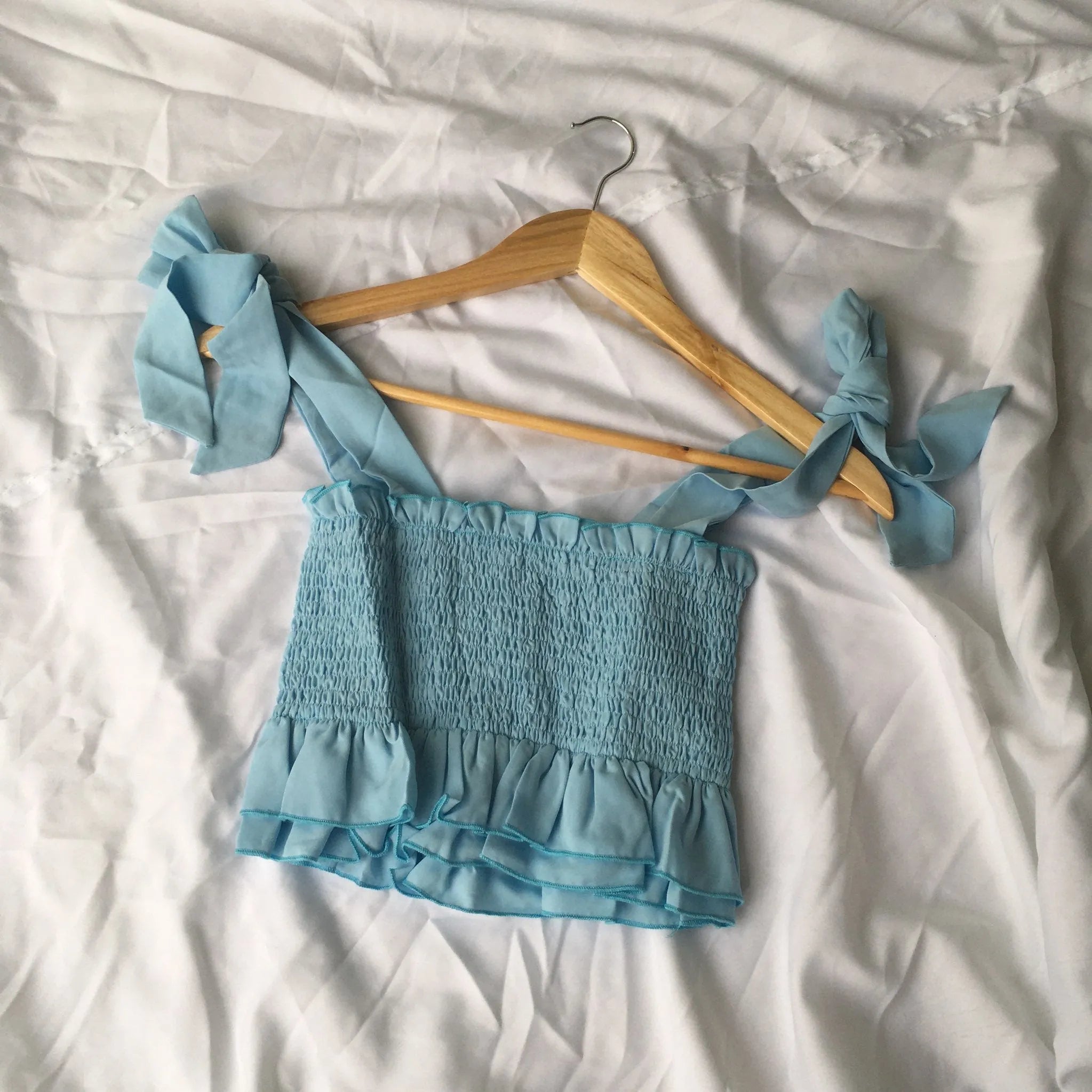 Blue top with ruffled straps on a wooden hanger against a white background - BlackBole High Quality western Dress