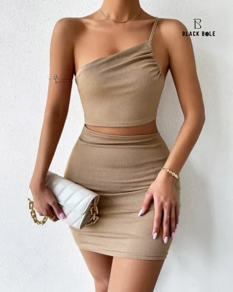 Woman wearing a beige one-shoulder top and skirt set with a white clutch against a light background - BlackBole High Quality western Dress