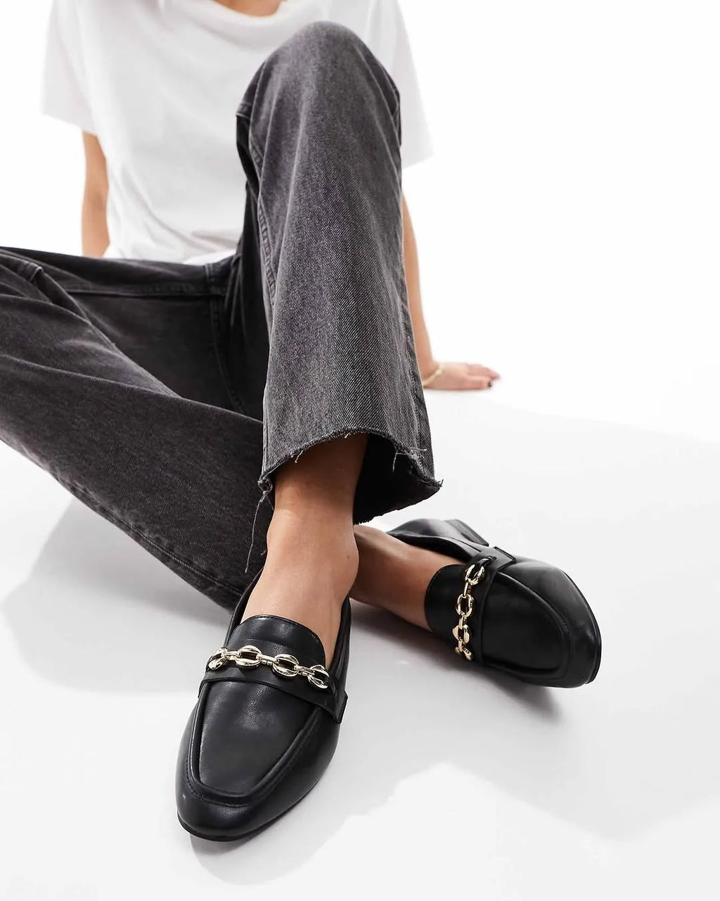Person wearing black loafers with chain details on a white background - BlackBole High Quality Shoe