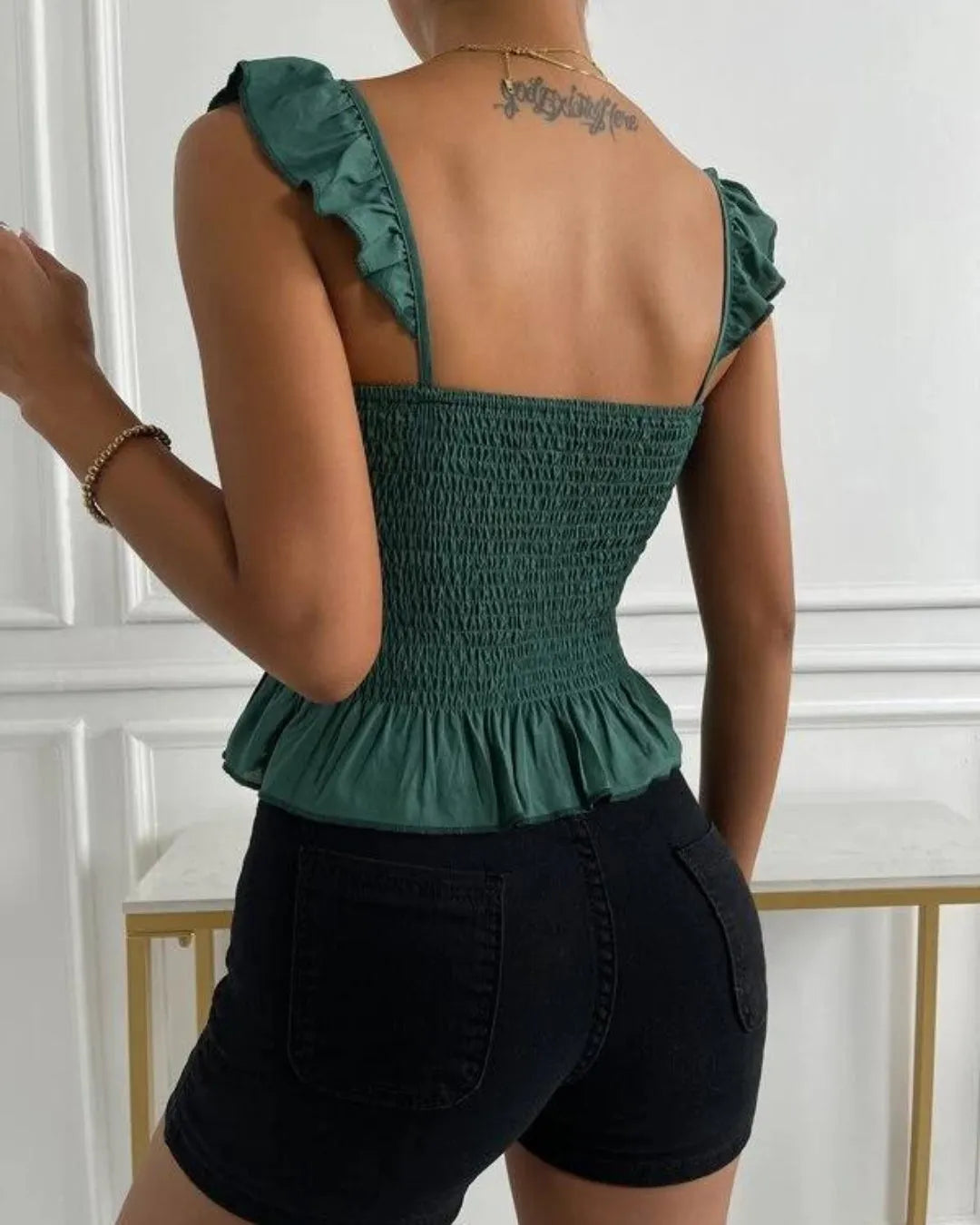 Person wearing a green smocked top with ruffled straps and black shorts against a white wall - BlackBole High Quality Western Dress