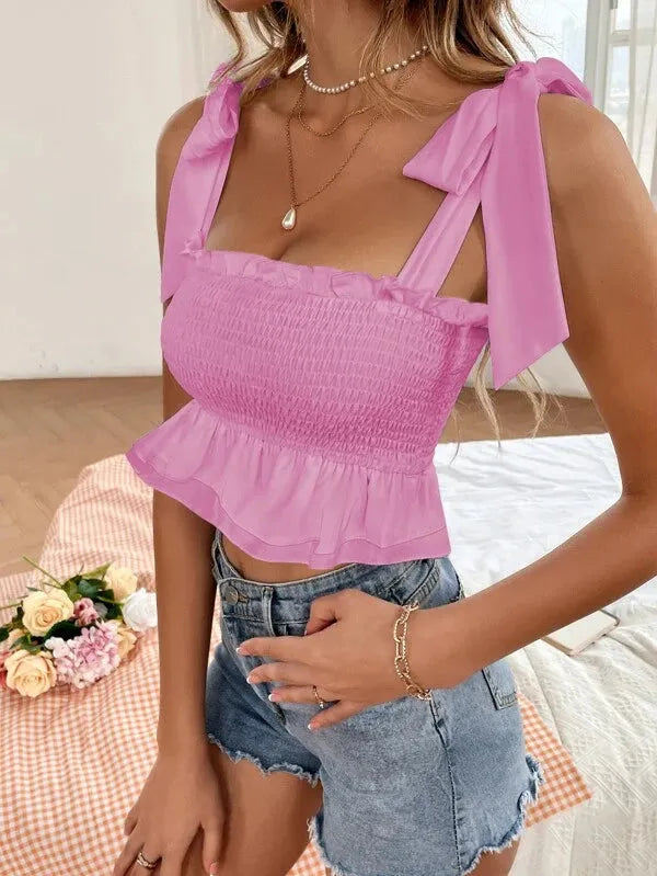 Woman wearing a pink smocked top with bow straps and denim shorts, standing on a checkered surface with flowers - BlackBole High Quality Western Dress