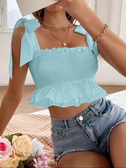 Person wearing a light blue top with ruffled details and denim shorts, sitting on a bed with flowers - BlackBole High Quality Western Dress